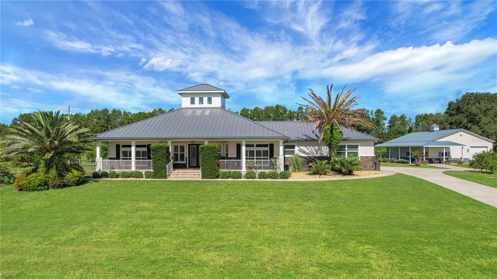 A single-story house with a metal roof and cupola sits behind a large green lawn — 16982 SE HIGHWAY 42, WEIRSDALE, FL
