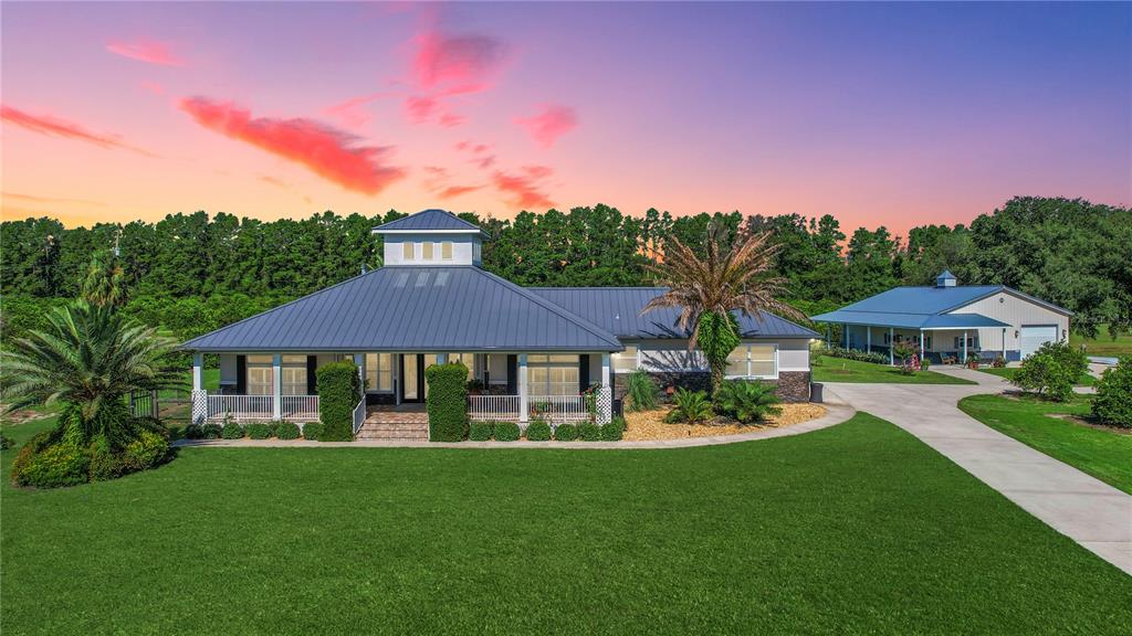 A single-story house with a metal roof and cupola sits beside a detached garage — 16982 SE HIGHWAY 42, WEIRSDALE, FL