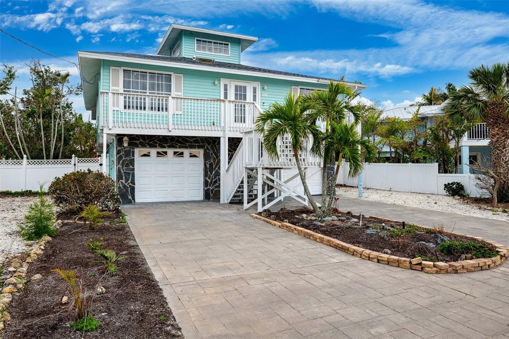 A two-story light blue house with a white garage door and a paved driveway — 311 POINSETTIA ROAD, ANNA MARIA, FL