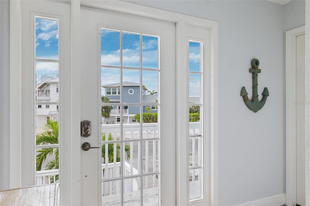 A white front door with glass panes and sidelights features a decorative anchor wall hanging — 311 POINSETTIA ROAD, ANNA MARIA, FL