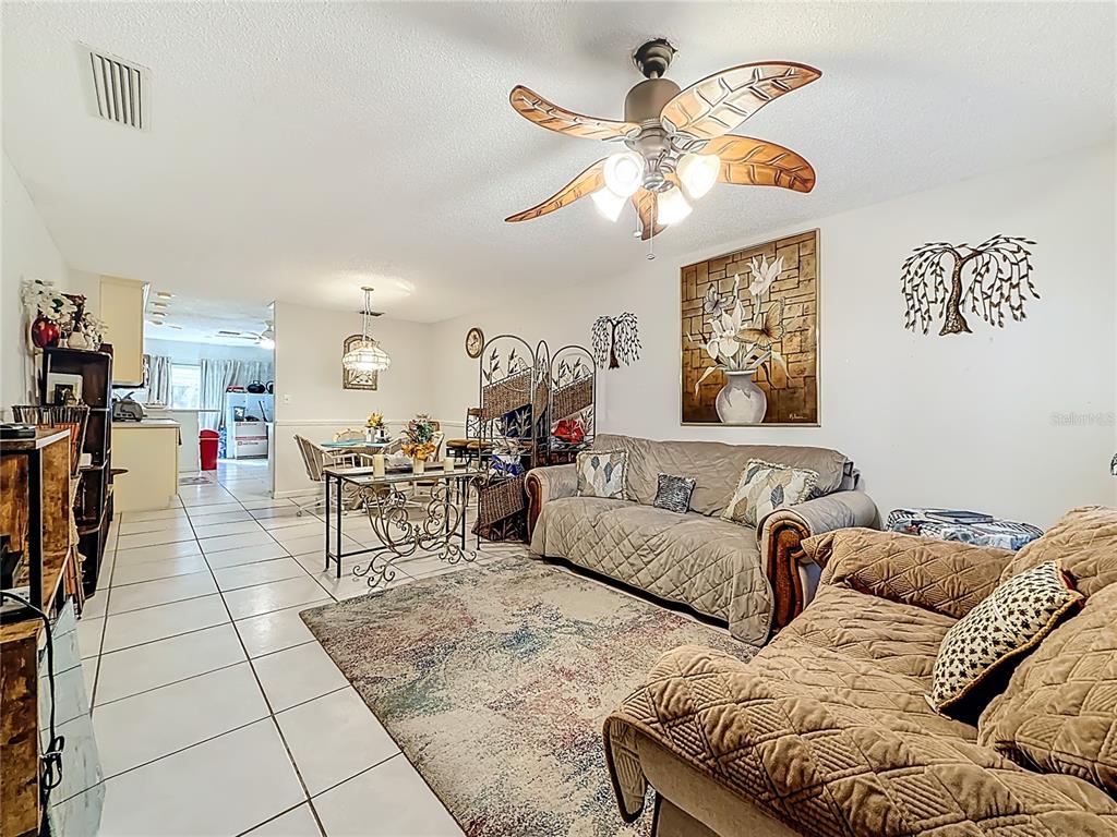 A living room with tile floors, a leaf-shaped ceiling fan, and two brown sofas — 1020 85TH AVENUE N UNIT 119, ST PETERSBURG, FL