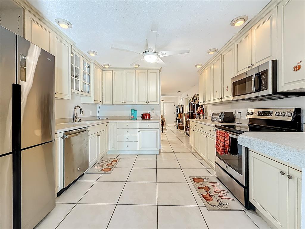 A kitchen with white cabinets, stainless steel appliances, and light-colored tile flooring — 1020 85TH AVENUE N UNIT 119, ST PETERSBURG, FL