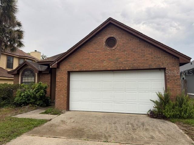 A single-story brick house features a two-car garage and a small circular vent in the gable — 2218 BARKWOOD COURT, LAKE MARY, FL