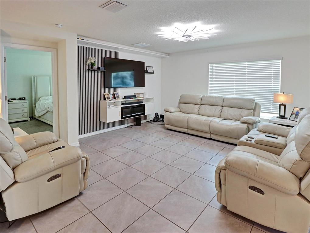 A living room features light tile floors, a slatted accent wall, and three leather recliners — 1202 TAHITIAN SUNRISE DRIVE, PLANT CITY, FL