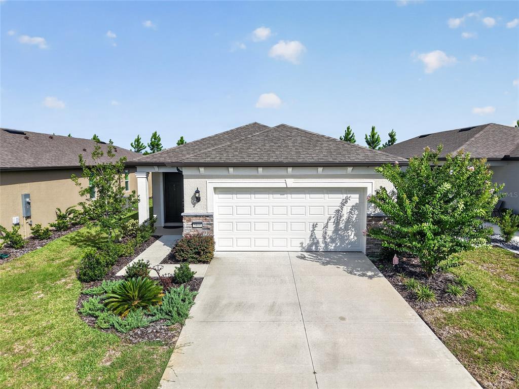 A single-story suburban house features a two-car garage, a concrete driveway, and landscaped front yard — 5866 SW 87TH AVENUE, OCALA, FL