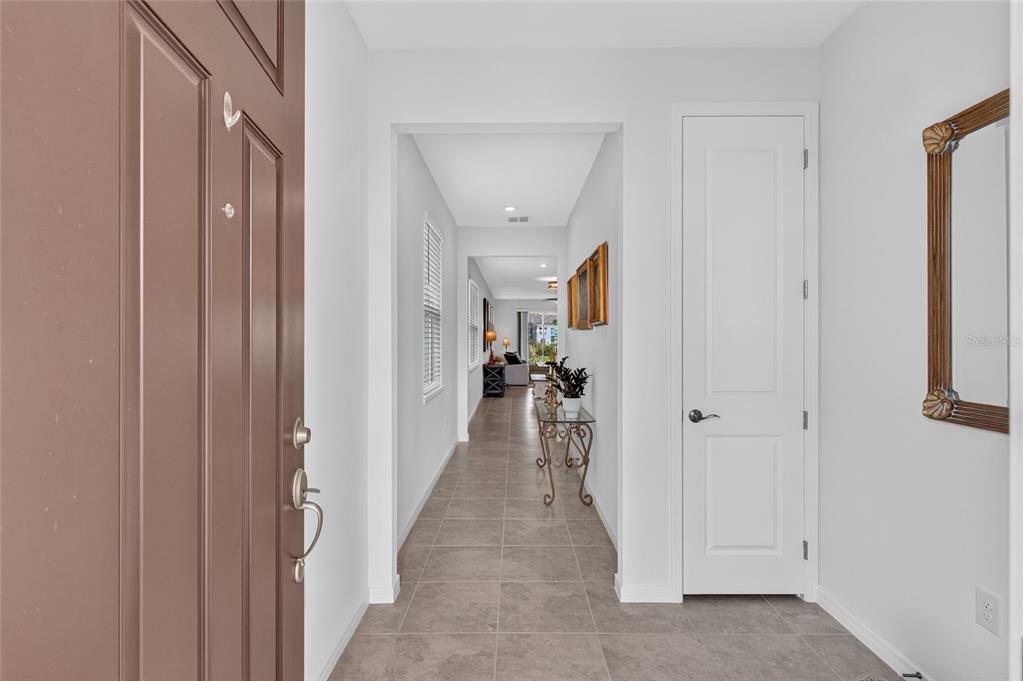 A tiled entryway leads into a long hallway with a white door and wall mirror — 5866 SW 87TH AVENUE, OCALA, FL