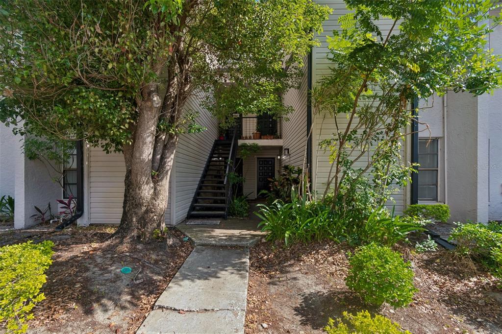 A concrete walkway leads to an outdoor staircase and a ground-level entrance of a building — 4745 PURITAN CIRCLE UNIT 4745, TAMPA, FL