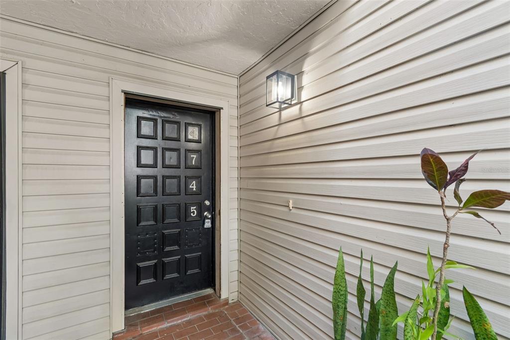 A black front door with a grid pattern and house numbers sits beside beige siding — 4745 PURITAN CIRCLE UNIT 4745, TAMPA, FL