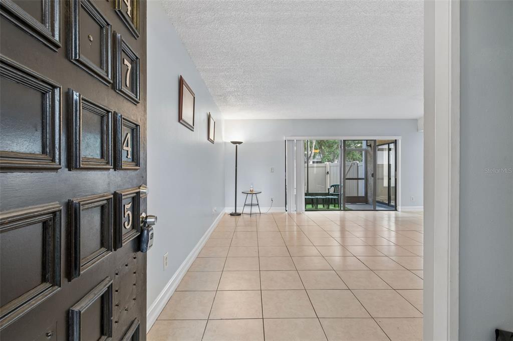 An open living area features light-colored tile floors, a floor lamp, and a sliding glass door — 4745 PURITAN CIRCLE UNIT 4745, TAMPA, FL