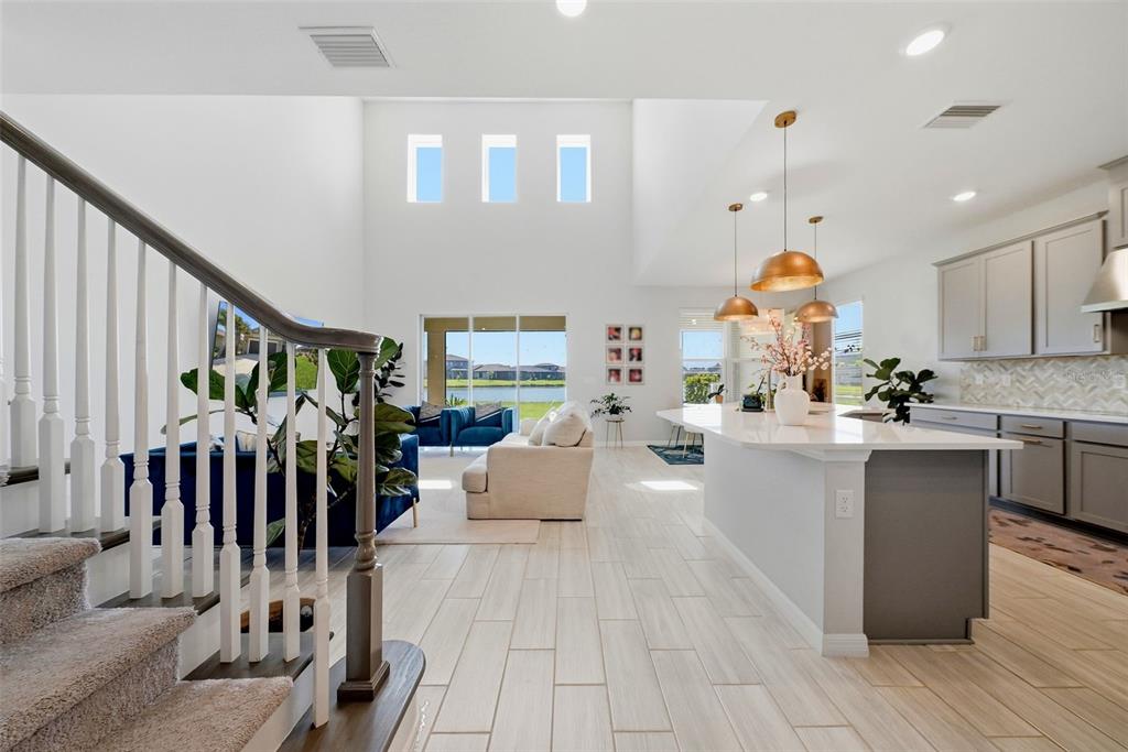 An open-concept living area features a kitchen with a large island and a high-ceilinged living room — 33773 ASTORIA CIRCLE, WESLEY CHAPEL, FL