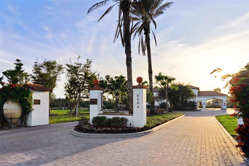 A paved driveway leads through a gated entrance with palm trees and white stucco pillars — 11120 HACIENDA DEL MAR BOULEVARD UNIT F-205, PLACIDA, FL