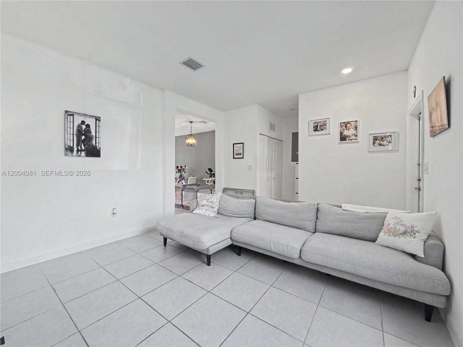 A living room features light gray tile flooring, white walls, and a large gray sectional sofa — 14800 SW 183rd Ter, Miami FL 33187, MIAMI, FL
