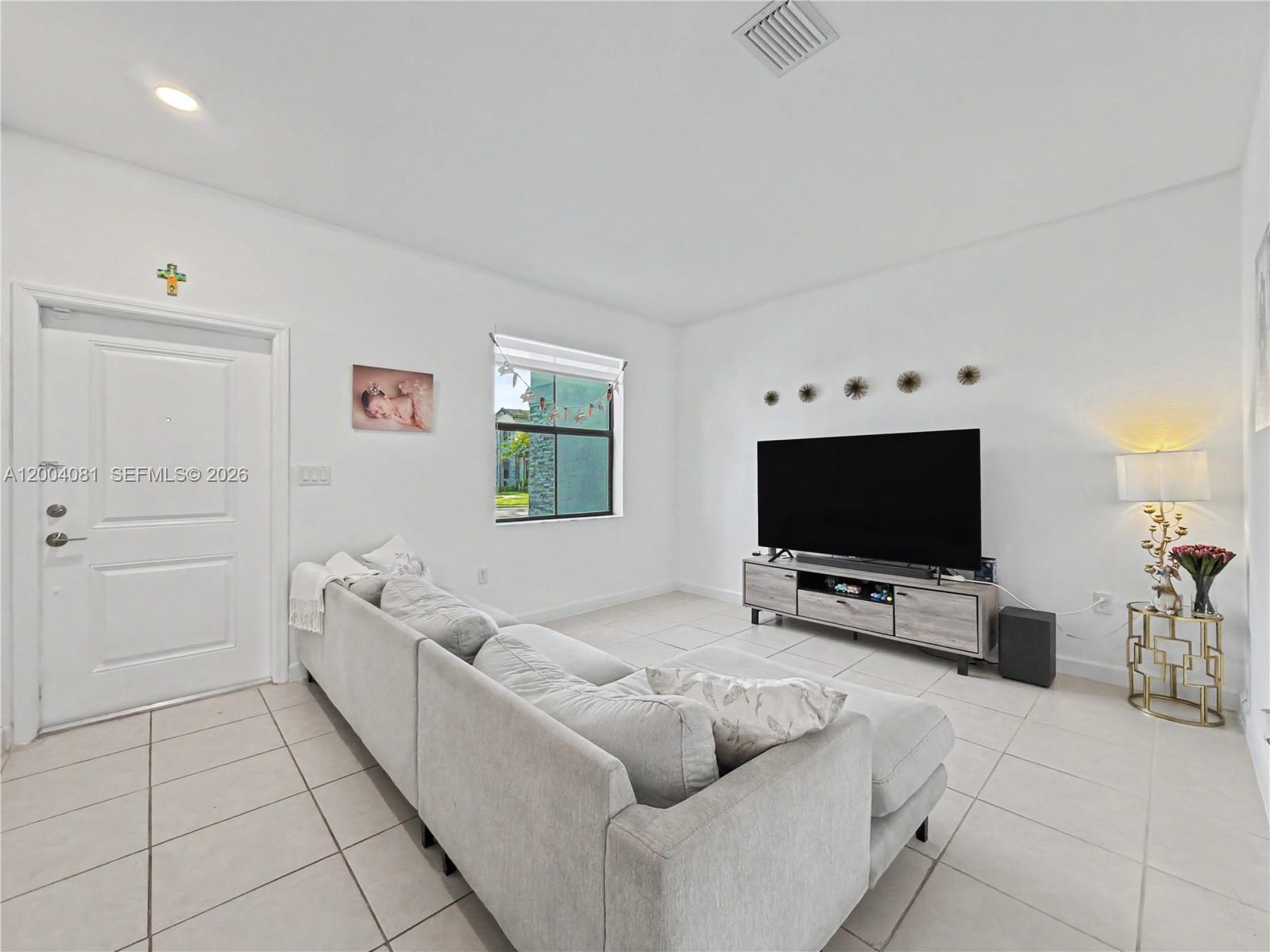 A living room features white walls, tile flooring, a sectional sofa, and a television console — 14800 SW 183rd Ter, Miami FL 33187, MIAMI, FL
