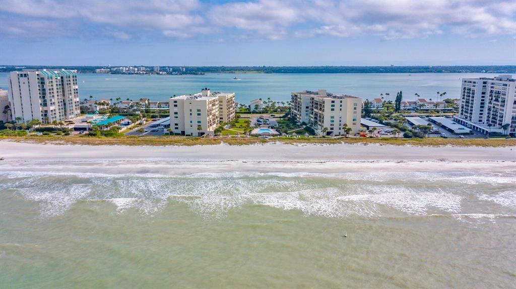 An aerial view of beachfront condominium buildings along a sandy coastline with ocean waves — 1430 GULF BOULEVARD UNIT 108, CLEARWATER, FL