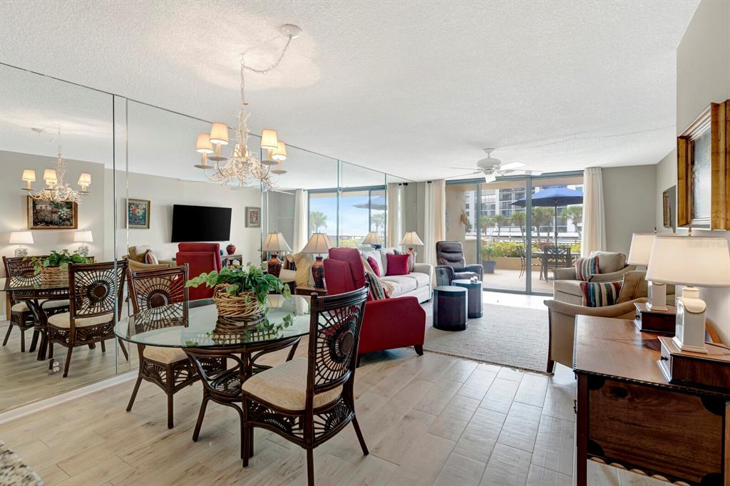 A living and dining area features mirrored walls, tile flooring, and a balcony with ocean views — 1430 GULF BOULEVARD UNIT 108, CLEARWATER, FL