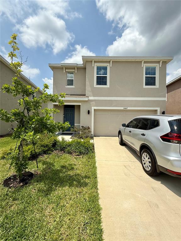 A two-story house with a beige exterior, a two-car garage, and a silver SUV parked — 30807 PENNY SURF LOOP, WESLEY CHAPEL, FL