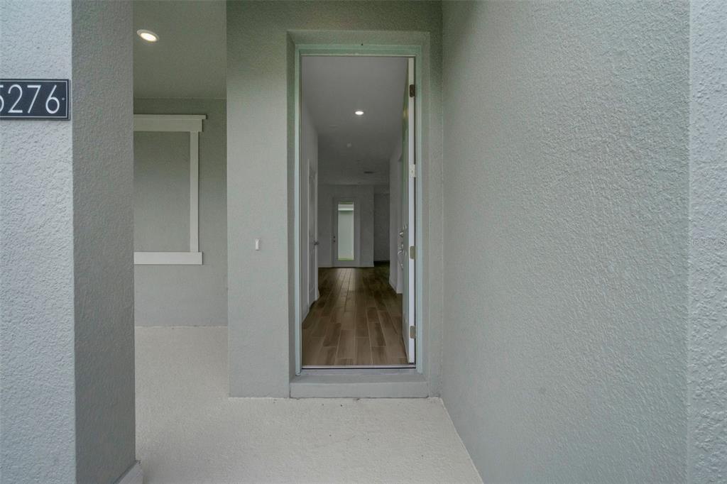 A view from a covered porch looking through an open front door into a hallway — 5137 BLANKET FLOWER STREET, APOPKA, FL