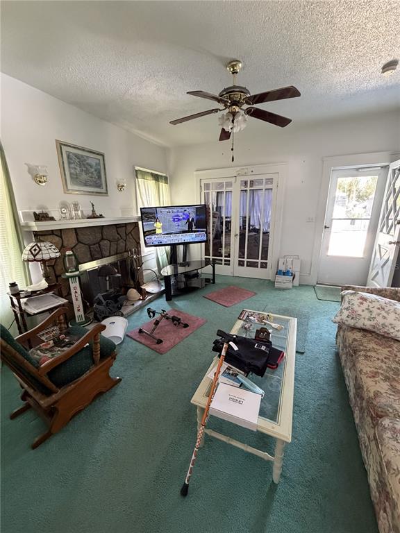 A living room features green carpet, a stone fireplace, a ceiling fan, and a television — 600 5TH AVENUE, DAYTONA BEACH, FL
