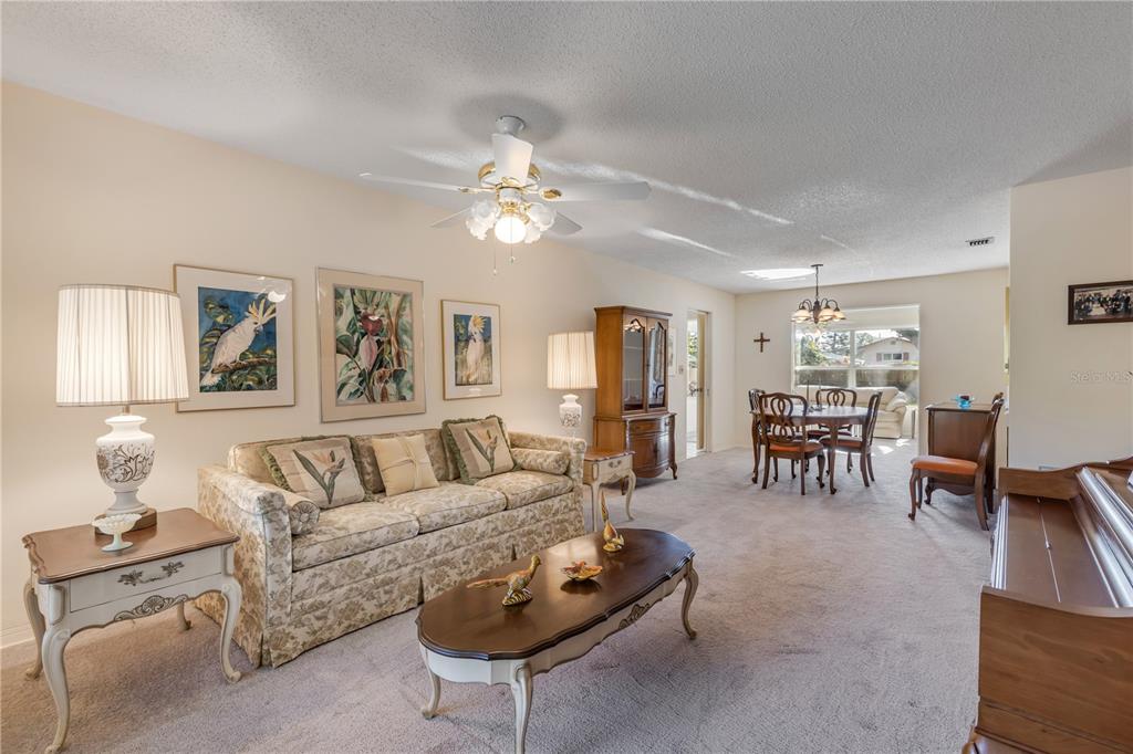 A living room with a floral sofa, coffee table, dining area, and beige carpeting — 535 S PENINSULA AVENUE, NEW SMYRNA BEACH, FL