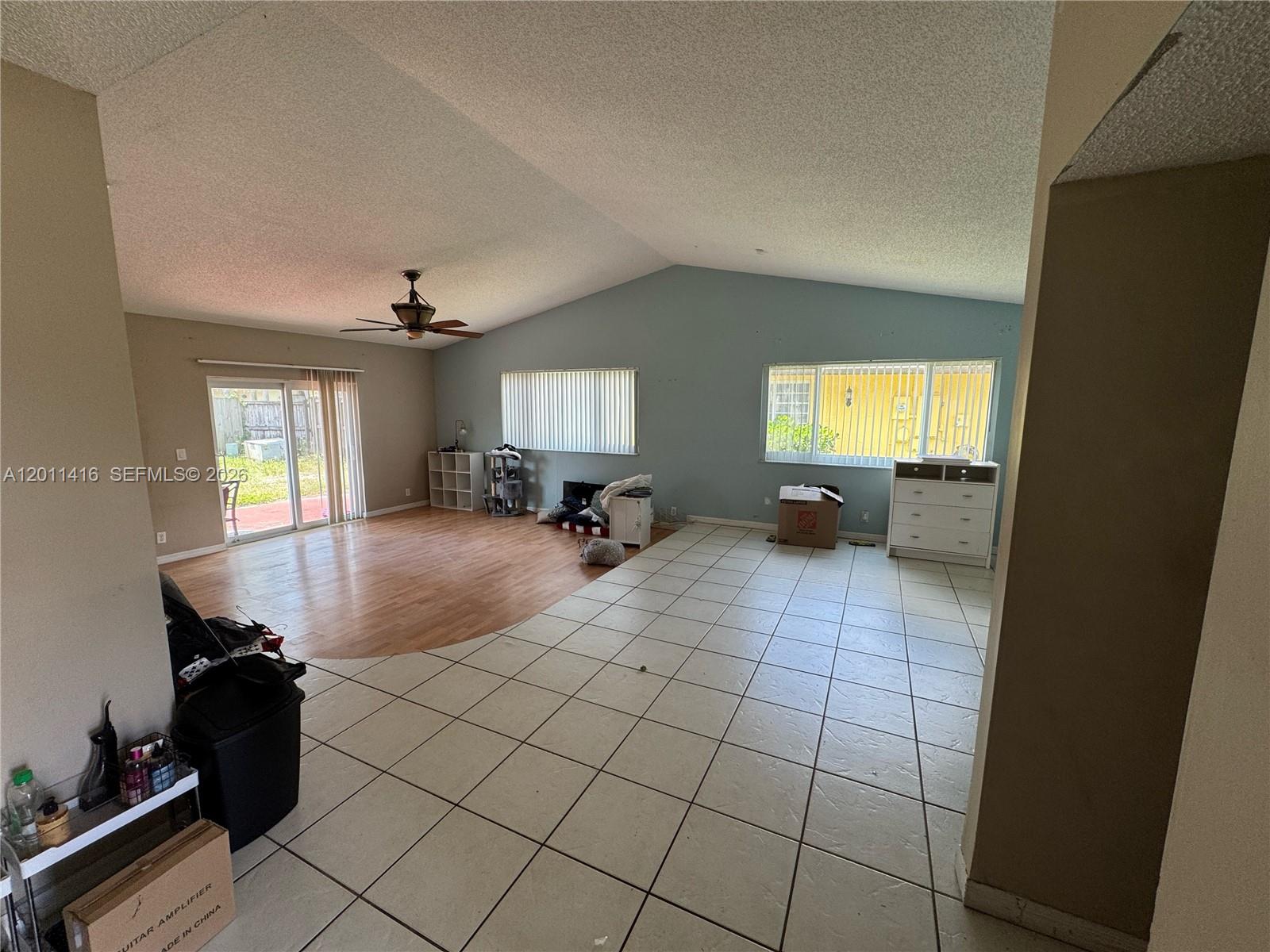 A living room features a vaulted ceiling, tile and wood flooring, and sliding glass doors — 8700 NW 46th Ct, Lauderhill FL 33351, LAUDERHILL, FL