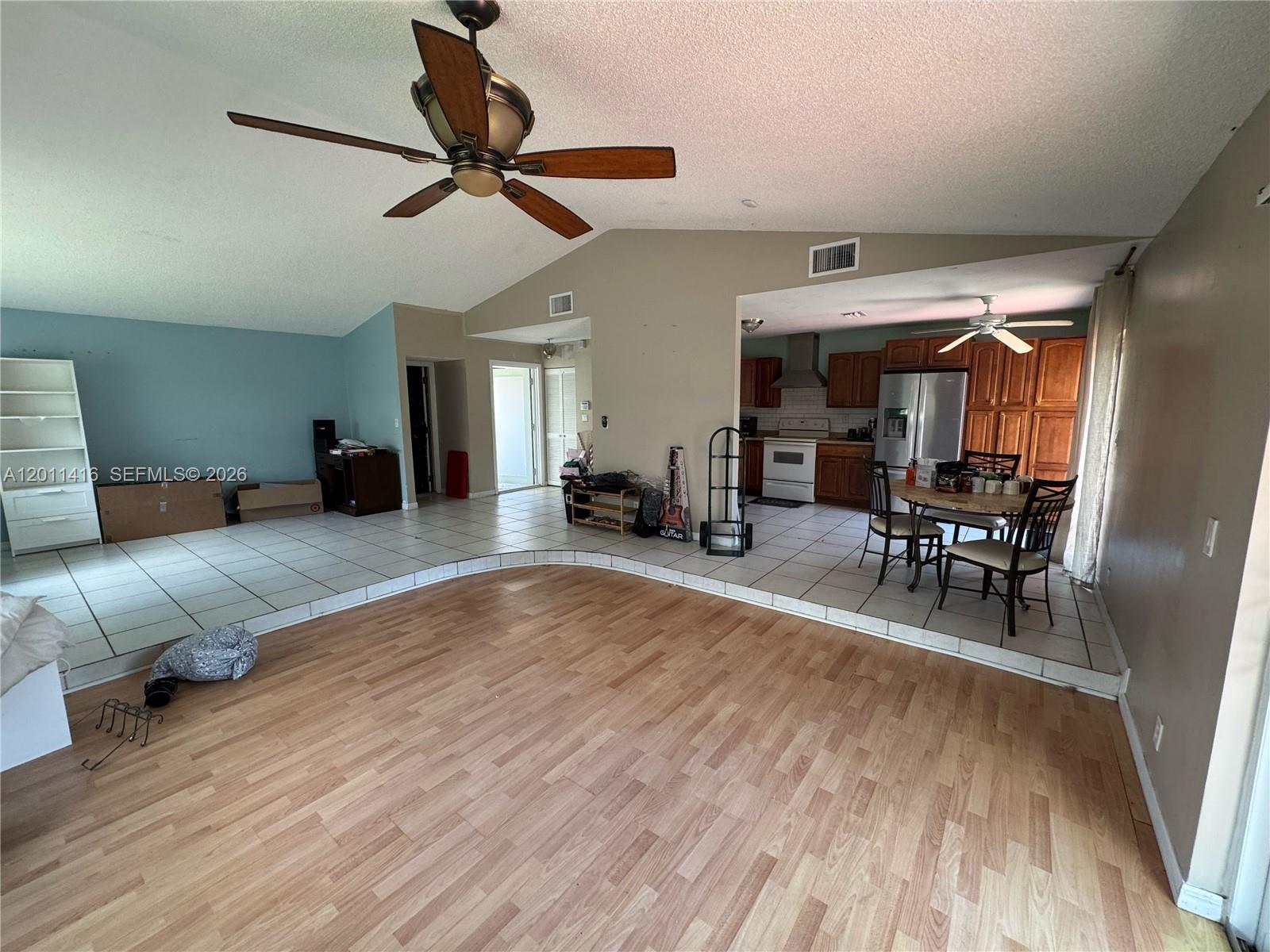 A sunken living room with wood flooring transitions to a tiled kitchen and dining area — 8700 NW 46th Ct, Lauderhill FL 33351, LAUDERHILL, FL