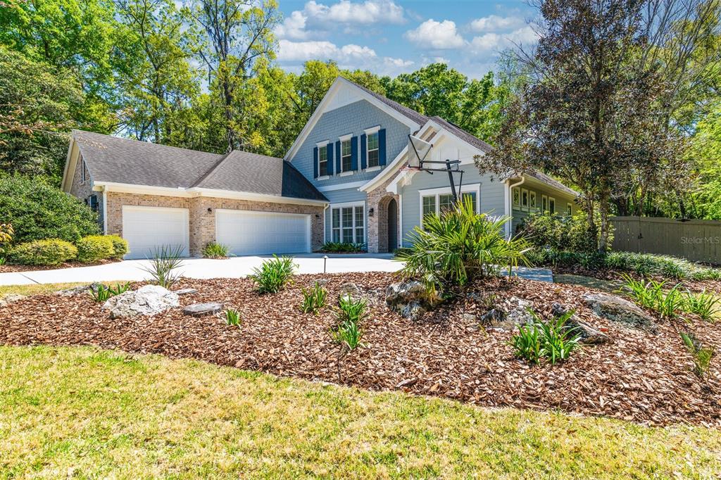 A two-story house with a blue shingle exterior, brick accents, and a three-car garage — 10257 SW 37TH PLACE, GAINESVILLE, FL