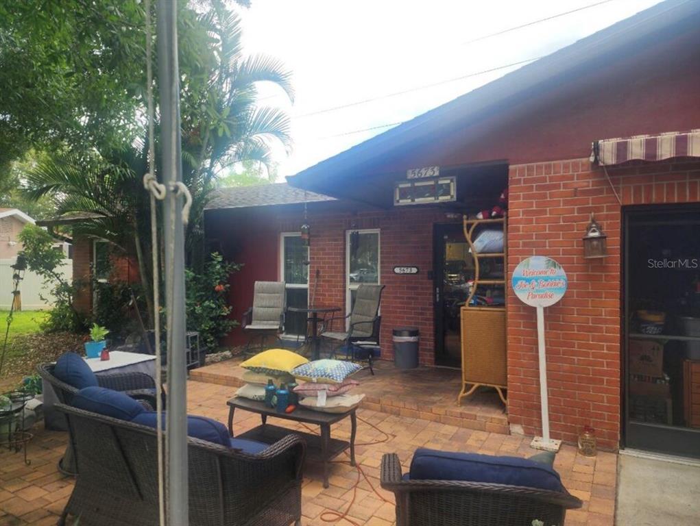 A brick patio features outdoor furniture, a small table, and a welcome sign — 5673 97TH WAY N, ST PETERSBURG, FL