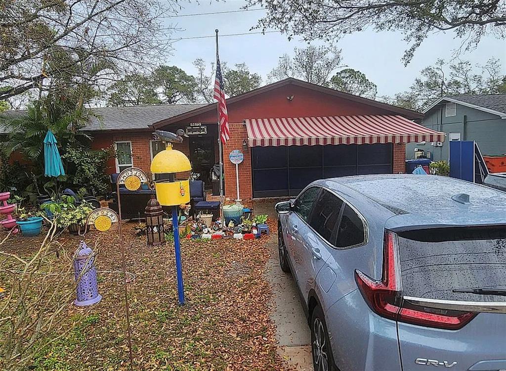 A single-story brick house with a striped awning over the garage and a front yard — 5673 97TH WAY N, ST PETERSBURG, FL