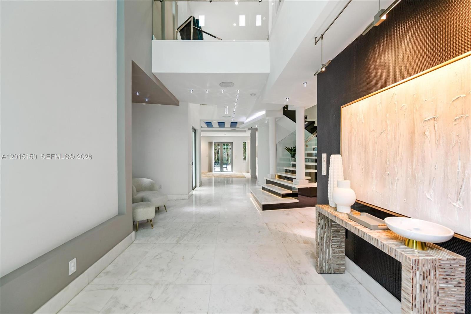 A spacious, modern entryway features marble floors, a floating staircase, and a textured accent wall — 3917 S Le Jeune Rd, Miami FL 33146, MIAMI, FL