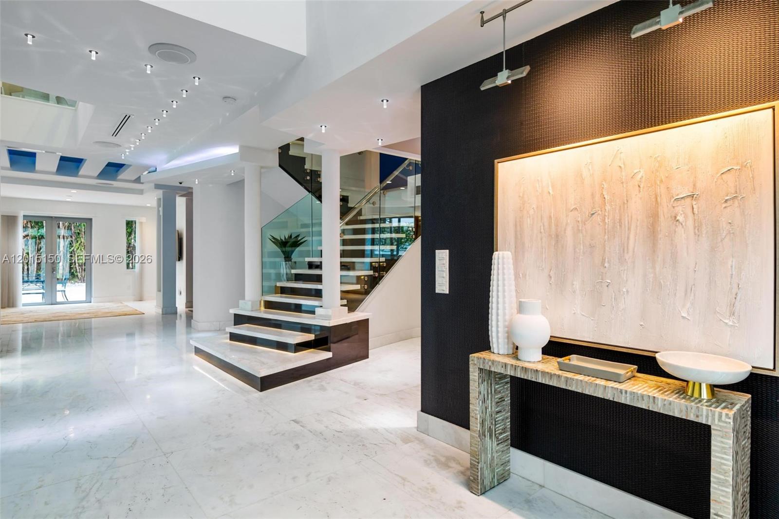 A modern entryway features a floating staircase, marble floors, and a textured black accent wall — 3917 S Le Jeune Rd, Miami FL 33146, MIAMI, FL