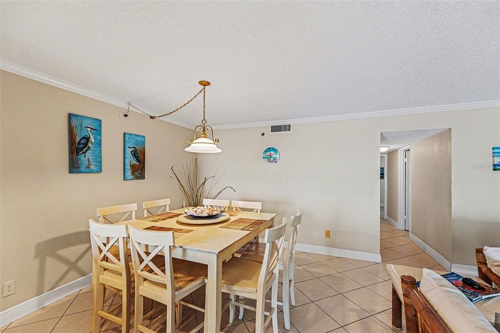 A dining room features a light-colored wooden table, six chairs, and a hanging pendant light — 19500 GULF BOULEVARD UNIT 102, INDIAN SHORES, FL
