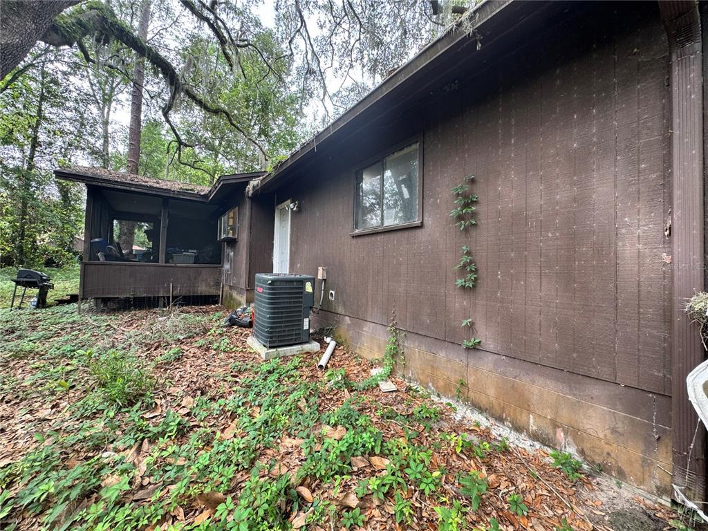 A living room features a brick fireplace with wood paneling, blue sofas, and a skylight — 713 NW 95TH TERRACE, GAINESVILLE, FL