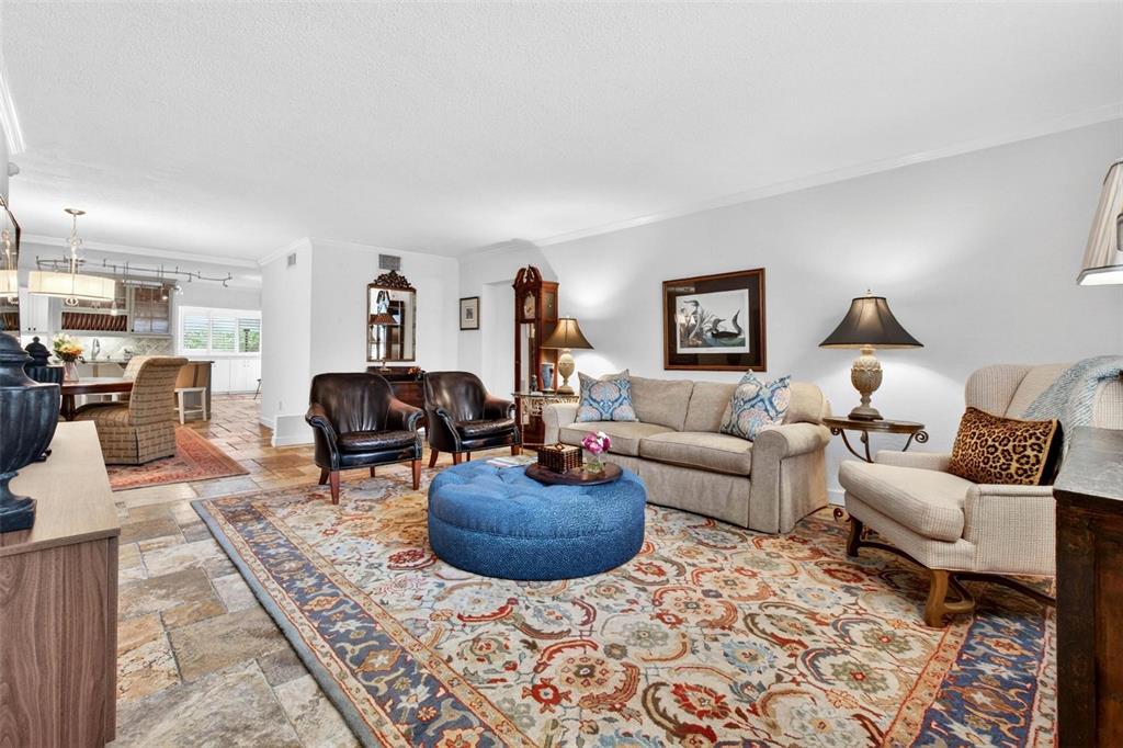 A living room features a large blue ottoman, patterned area rug, and stone tile flooring — 1065 EDEN ISLE BOULEVARD NE UNIT 2, ST PETERSBURG, FL