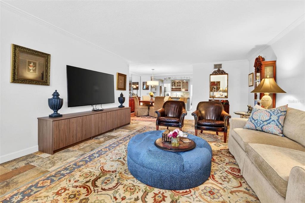 A living room features a large blue ottoman, leather armchairs, a television, and tile flooring — 1065 EDEN ISLE BOULEVARD NE UNIT 2, ST PETERSBURG, FL