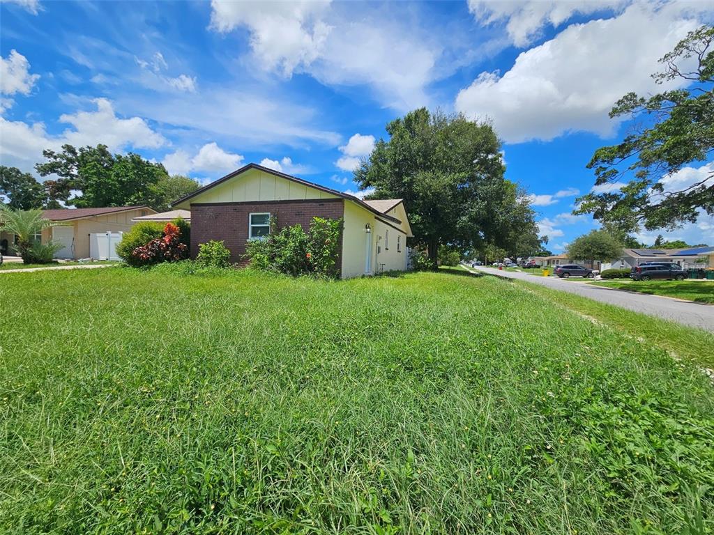 A single-story house with a brick and light-colored exterior sits on a large grassy lot — 6092 BURCH STREET N, ST PETERSBURG, FL