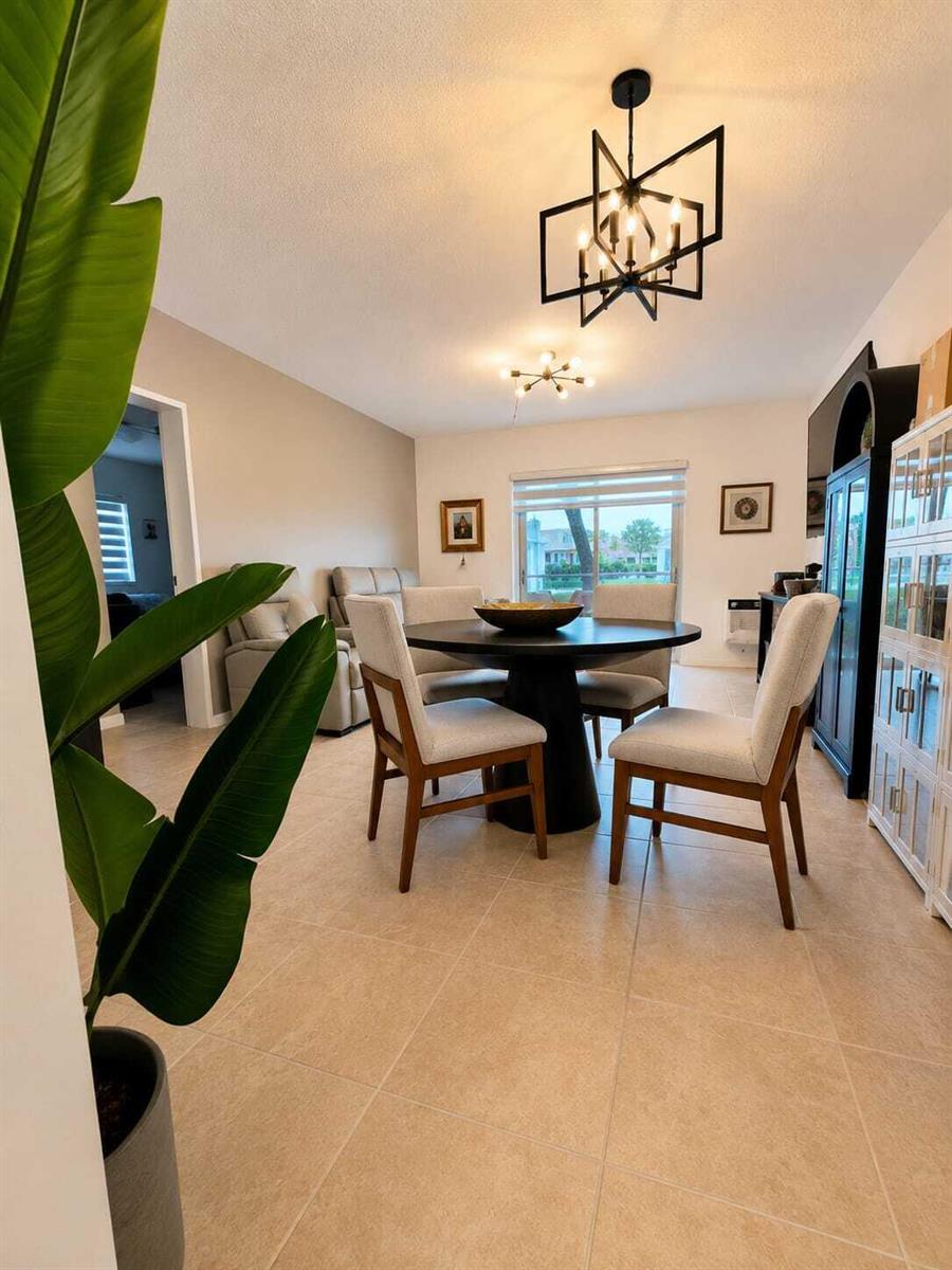 A dining area features a round table, four upholstered chairs, and a geometric chandelier — 16900 NE 14th Avenue # 115, Miami FL 33162, MIAMI, FL