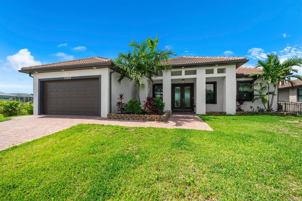 A single-story house with a brown garage, white stucco walls, and a tiled roof — 15504 HENNIPEN CIRCLE, PORT CHARLOTTE, FL