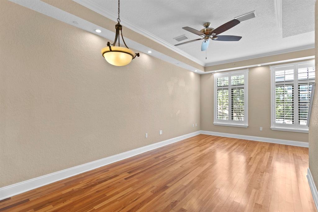 An empty room with hardwood floors, a ceiling fan, a pendant light, and plantation shutters — 2226 SOHO BAY COURT, TAMPA, FL