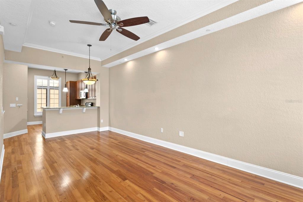 An empty living room with hardwood floors, a ceiling fan, and an open kitchen area — 2226 SOHO BAY COURT, TAMPA, FL
