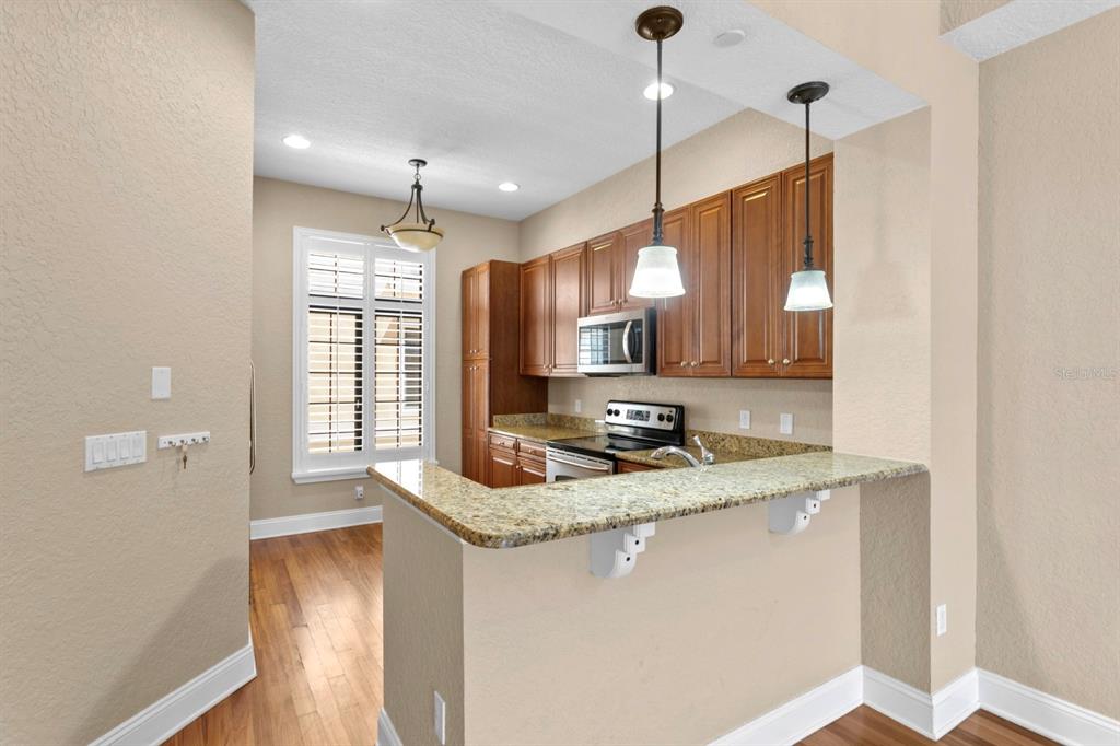 A kitchen features wood cabinets, granite countertops, a breakfast bar, and hardwood flooring — 2226 SOHO BAY COURT, TAMPA, FL