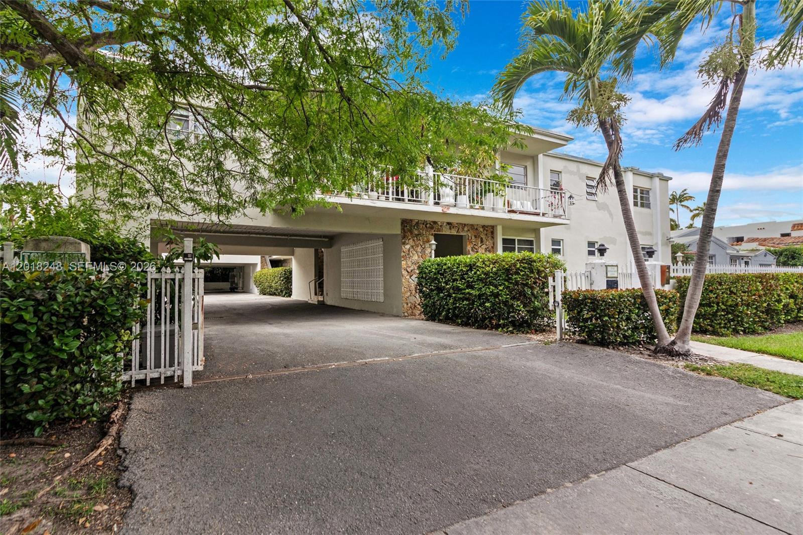An exterior view of a two-story apartment building with a covered parking area and palm trees — 1740 Jefferson Ave # 8, Miami Beach FL 33139, MIAMI BEACH, FL