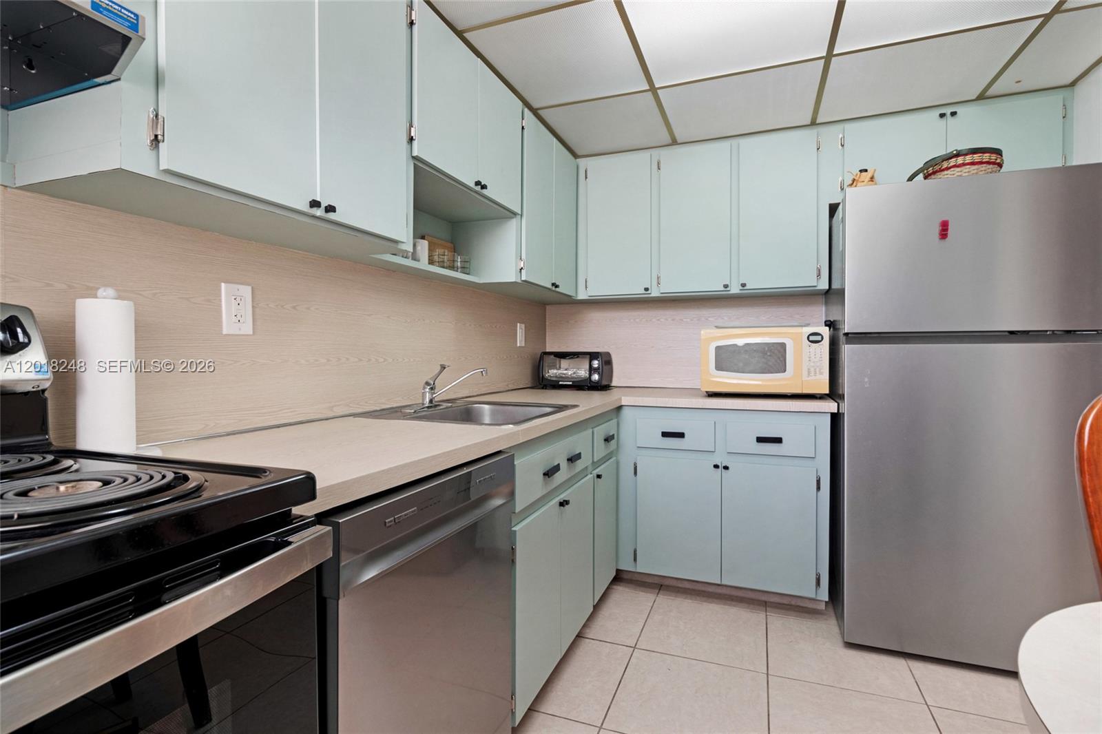 A kitchen features light blue cabinets, stainless steel appliances, and a light-colored laminate countertop — 1740 Jefferson Ave # 8, Miami Beach FL 33139, MIAMI BEACH, FL