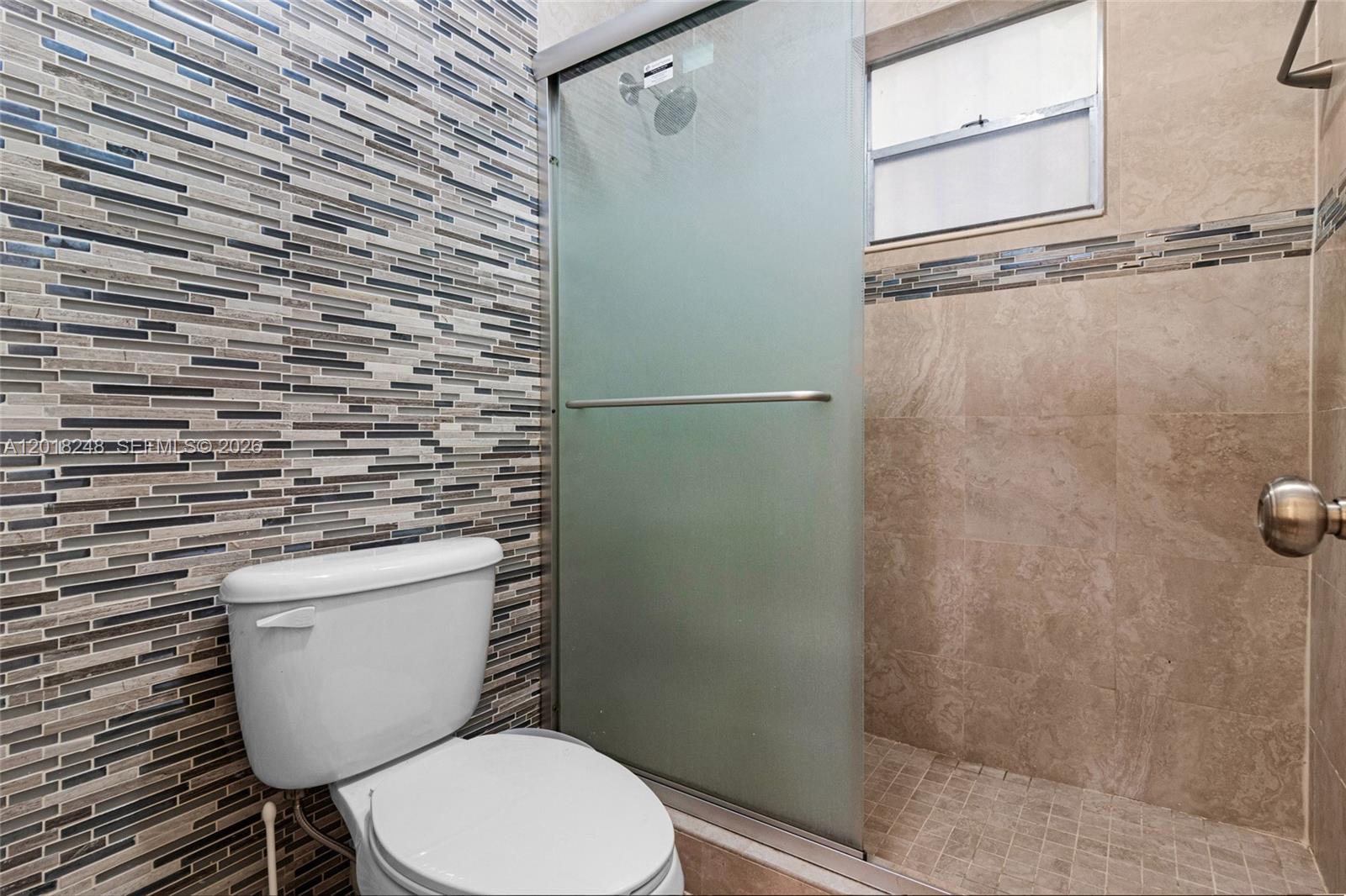 A bathroom features a toilet next to a glass-enclosed shower with tiled walls — 1740 Jefferson Ave # 8, Miami Beach FL 33139, MIAMI BEACH, FL