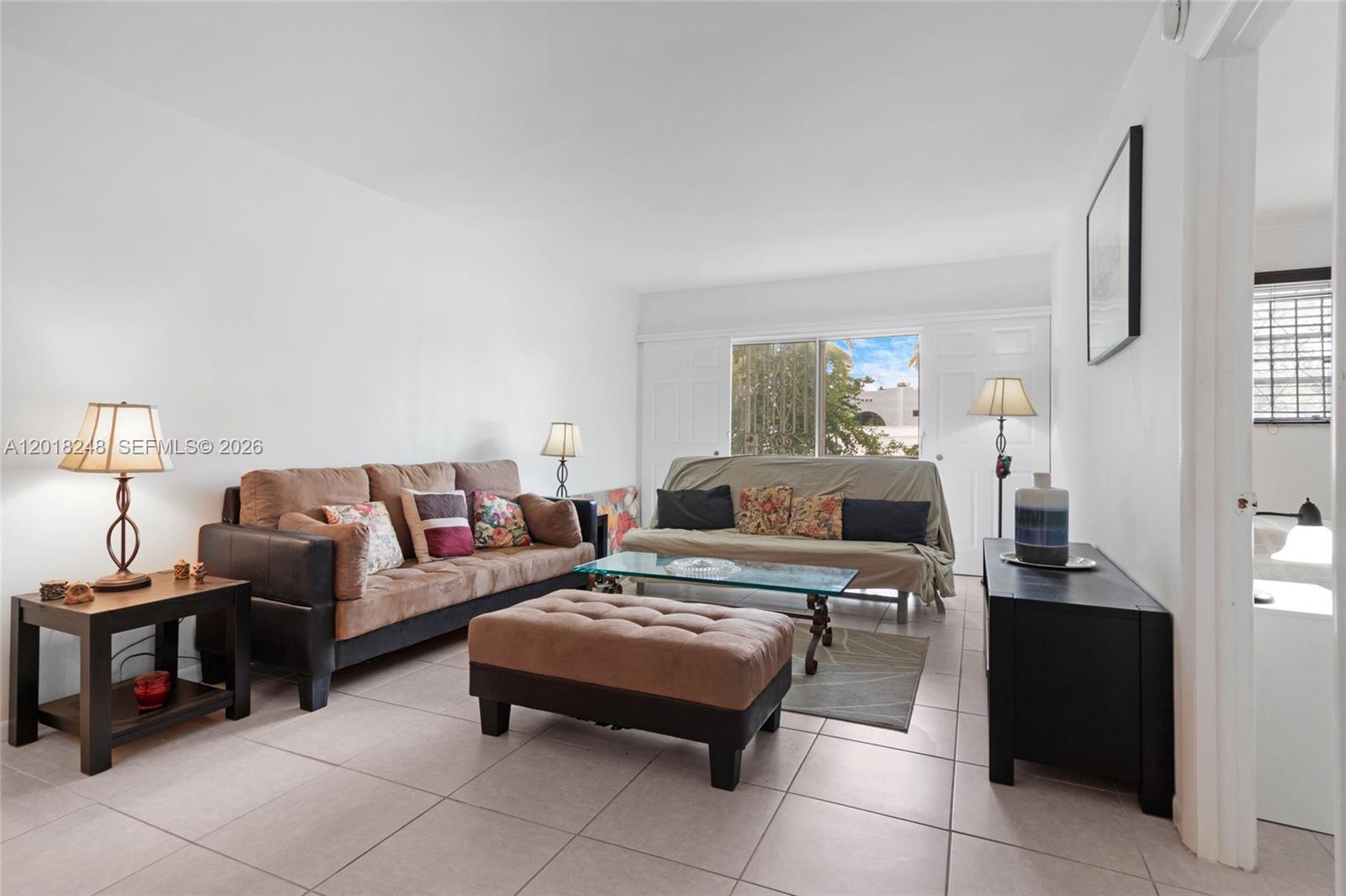 A living room features tile flooring, two sofas, a glass coffee table, and a sliding door — 1740 Jefferson Ave # 8, Miami Beach FL 33139, MIAMI BEACH, FL