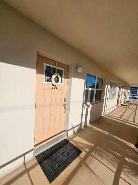 A light-colored exterior door with a wreath and a welcome mat on a walkway — 4565 DUHME ROAD UNIT 207, ST PETERSBURG, FL