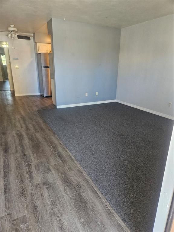 A living room features gray carpet, light blue walls, and adjacent wood-look vinyl flooring — 4565 DUHME ROAD UNIT 207, ST PETERSBURG, FL