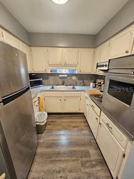 A galley kitchen features off-white cabinets, stainless steel appliances, and wood-look flooring — 4565 DUHME ROAD UNIT 207, ST PETERSBURG, FL