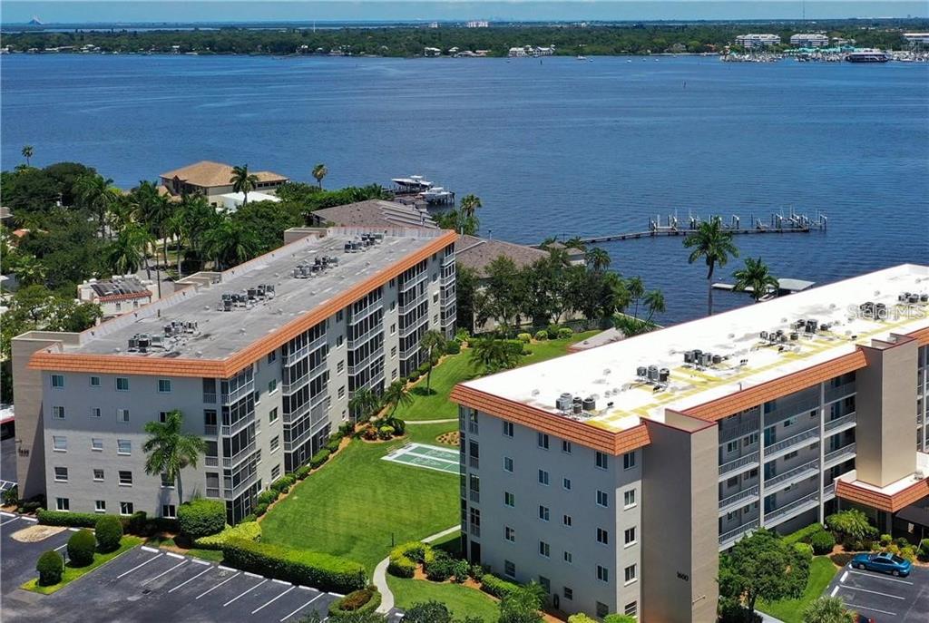 An aerial view of two multi-story apartment buildings with a grassy courtyard and waterfront access — 1650 1ST AVENUE W UNIT 507B, BRADENTON, FL