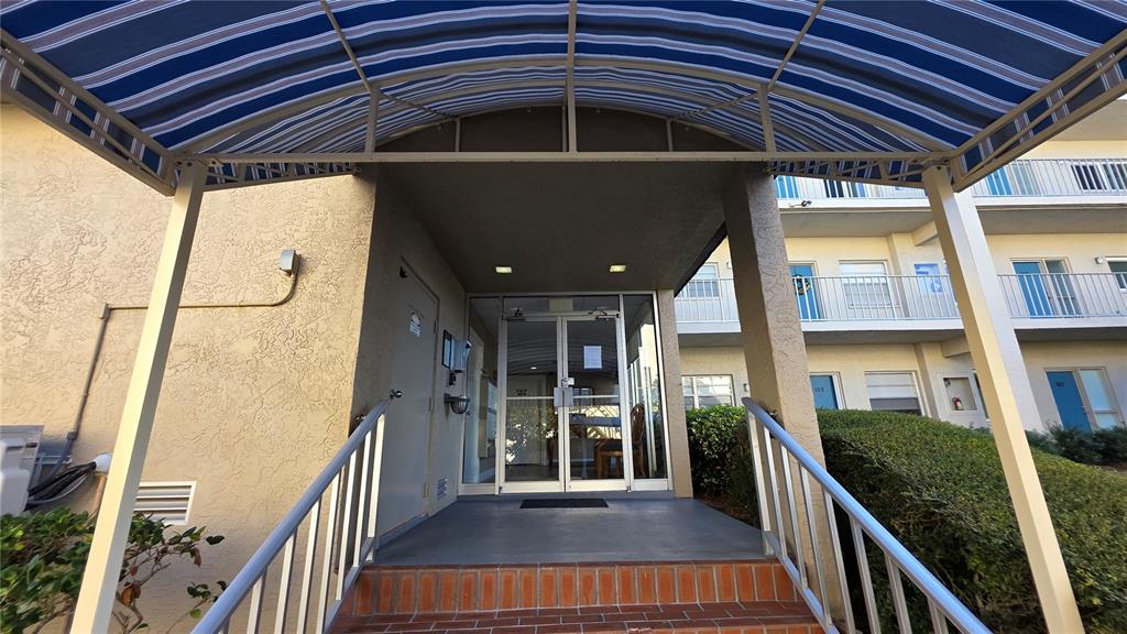 A covered entrance with a striped awning leads to a glass door and stairs — 1650 1ST AVENUE W UNIT 507B, BRADENTON, FL