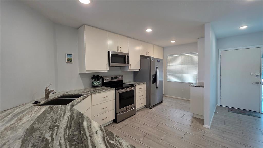 A kitchen features white cabinets, stainless steel appliances, and gray-veined granite countertops — 1650 1ST AVENUE W UNIT 507B, BRADENTON, FL